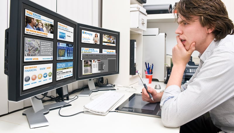 man looking at dual monitors of digital signage content